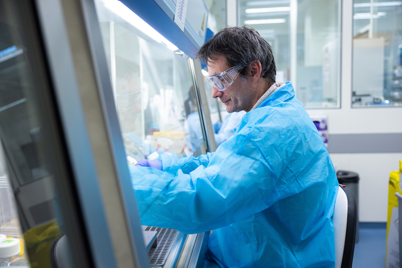 A scientist works in the lab under a hood, illustrating some of the practical work carried out during a radioligand binding assay
